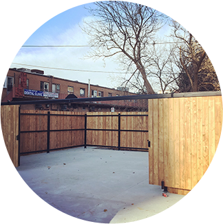 A fenced in area with trees and buildings behind it.